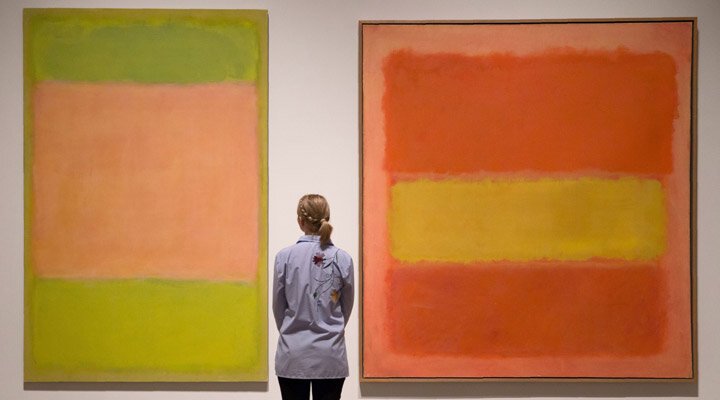 "A gallery assistant poses in front of paintings entitled 'Untitled, 1954' (L) and 'Untitled, 1949' by US artist Mark Rothko, during a photo call to promote Abstract Expressionism, an exhibition of paintings and sculptures, at the Royal Academy of A…